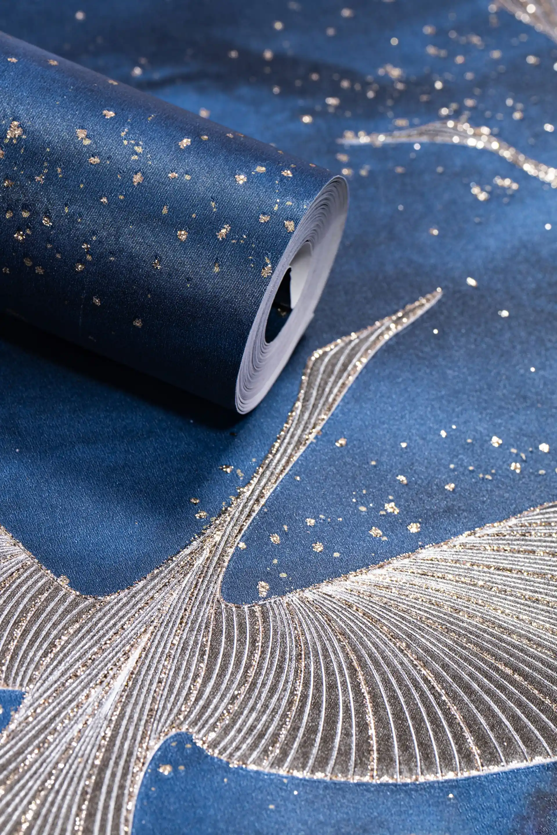 Deep blue wallpaper roll with silver and gold flying crane birds and scattered glitter on navy background